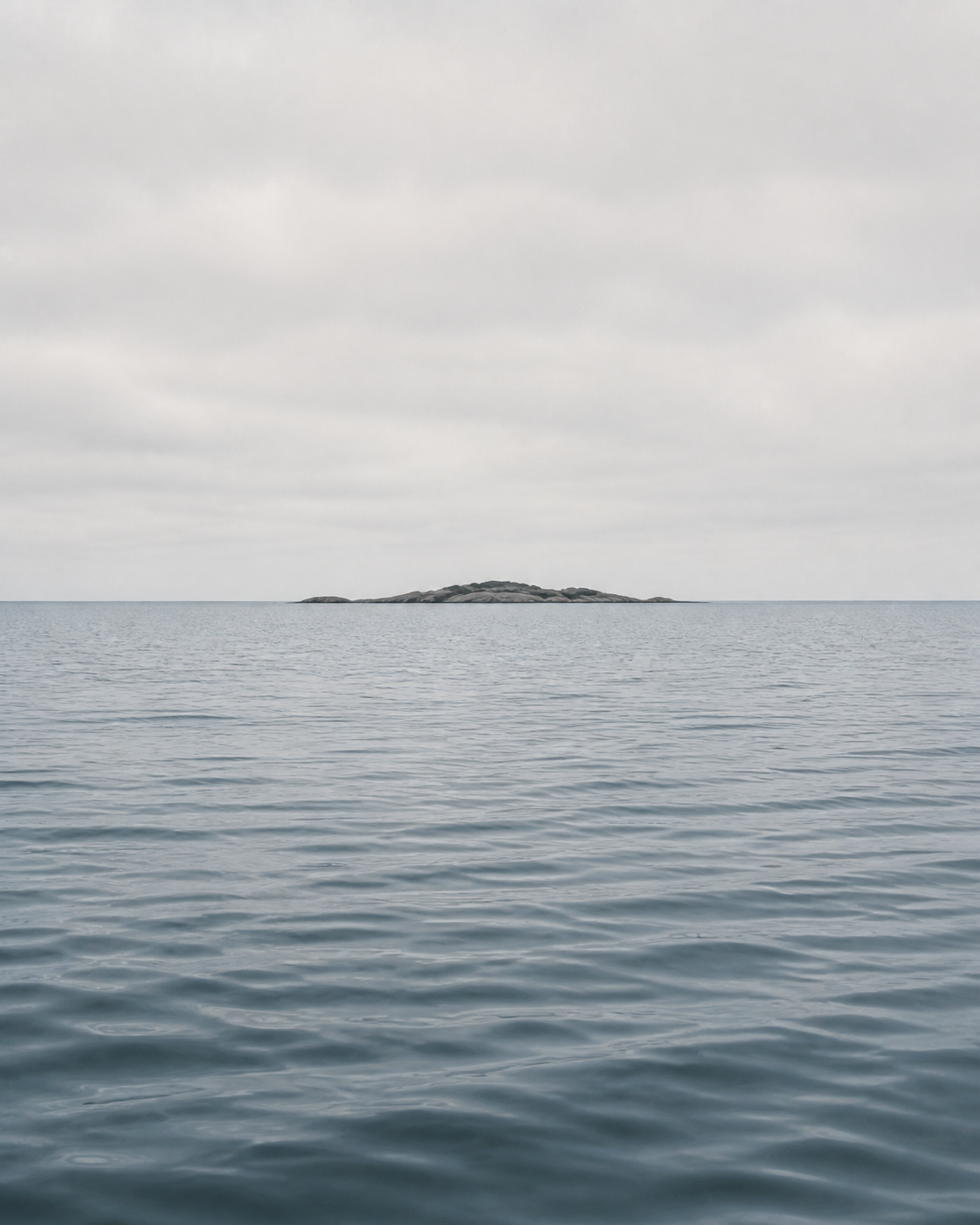 Calm Baltic water with a small rocky skerry on the horizon
